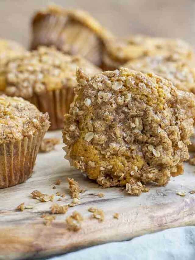 sourdough pumpkin muffins with a crumb topping spread in a wood cutting board on a green towel