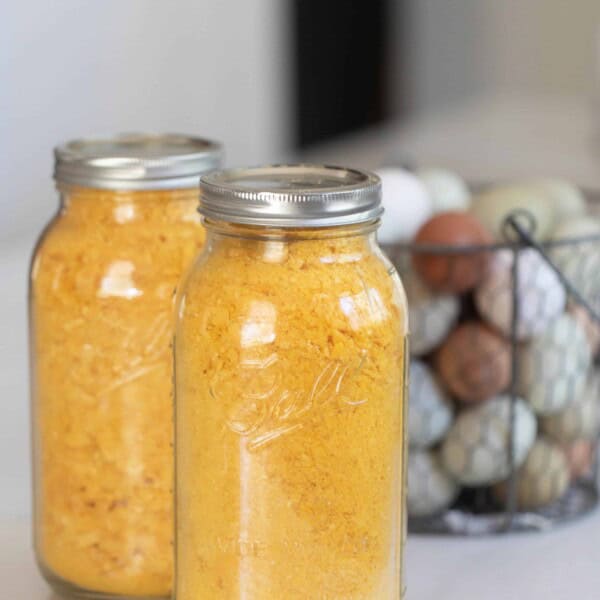 two jars of freeze dried eggs on a countertop with a basket full of eggs behind it