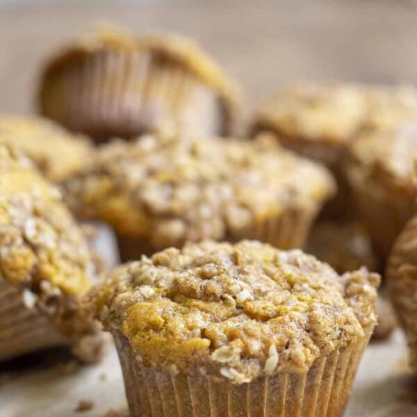 sourdough pumpkin muffin with oat crumb topping spread out on a wood cutting board on a wooden table