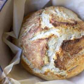 overhead photo of a boule of sourdough discard bread in a parchment lined dutch oven