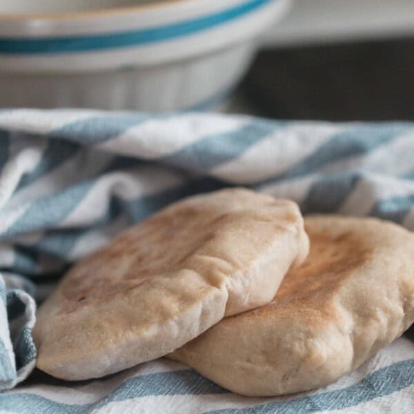 two sourdough pita bread on a white and blue stripped towel