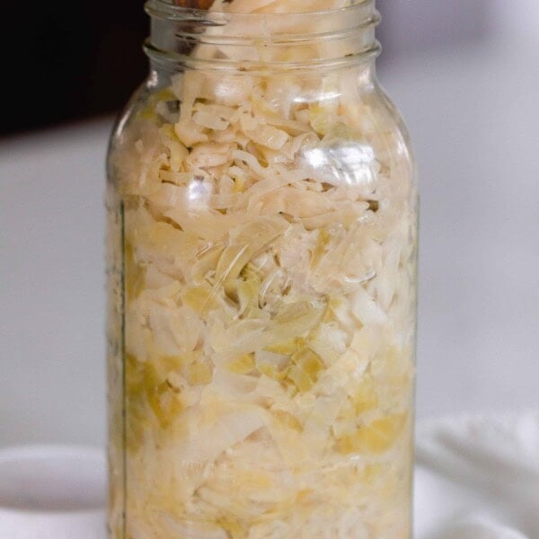 sauerkraut in a glas mason jar with a wooden spatula sticking out