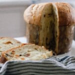 two slices cut out of one loaf of sourdough pannetone with a white and blue striped tea towel