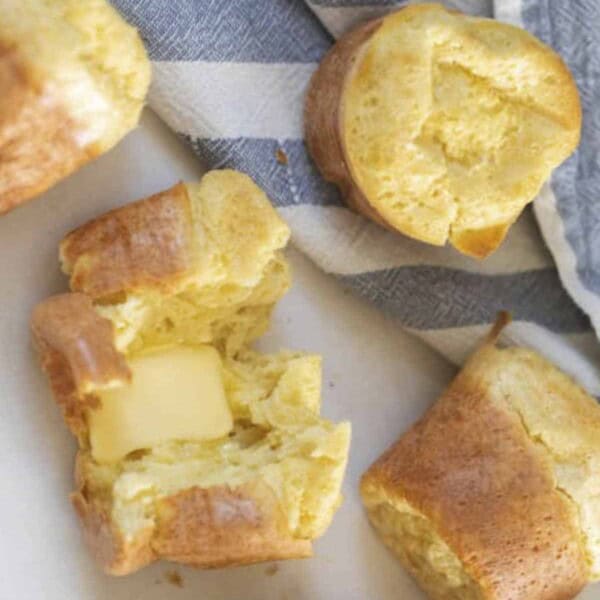 six sourdough popovers on a white countertop and blue and white stripped tea towel