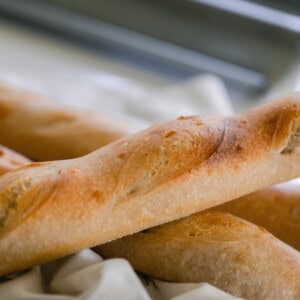 Sourdough baguette stacked on two other baguettes on a white tea towel