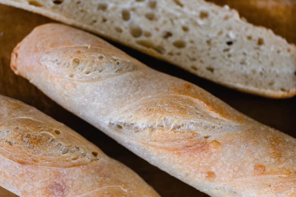three loaves of sourdough baguettes with one cut open