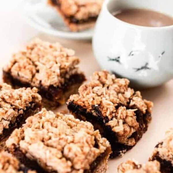 date bites cut into squares sitting on a table with a white mug of coffee in the background