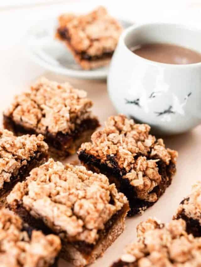 date bites cut into squares sitting on a table with a white mug of coffee in the background