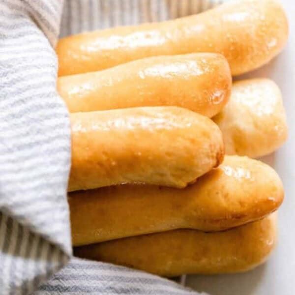 breadsticks sitting on a plate wrapped in a tea towel