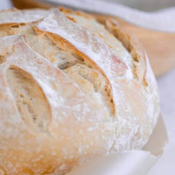 sourdough bread with a leaf pattern on parchment paper with a copper container to the left