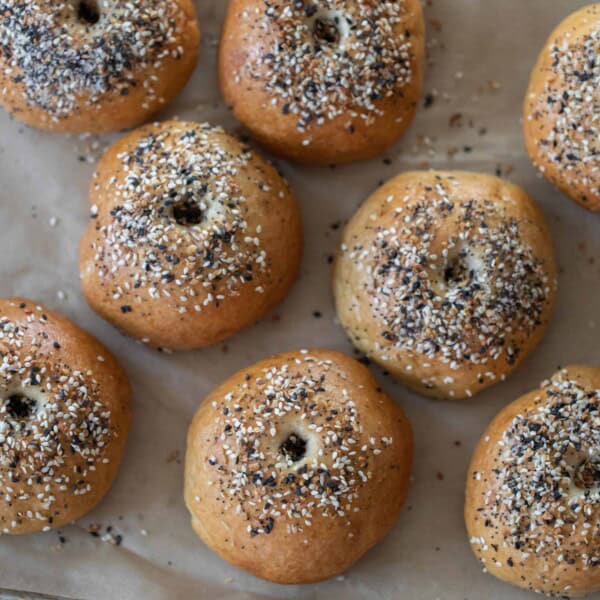 overhead photo of sourdough discard bagels topped with everything seasoning on a parchment lined baking sheet