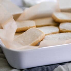 sourdough shortbread cookies stacked in a white casserole dish lined with parchment paper