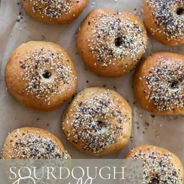 overhead photo of sourdough discard bagels topped with everything seasoning on a parchment lined baking sheet