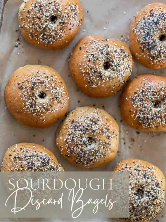 overhead photo of sourdough discard bagels topped with everything seasoning on a parchment lined baking sheet