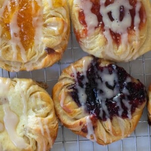 overhead photo of Danish sourdough pastries topped with cream cheese filling and jam and drizzled with a glaze on a wire rack