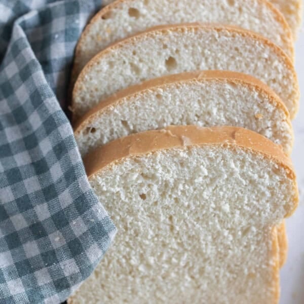 slices of sourdough buttermilk bread fanned out on a white and blue checked towel