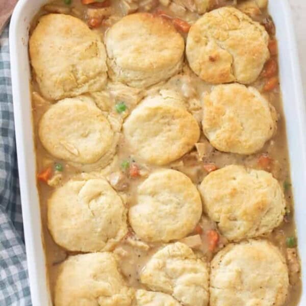 overhead photo of chicken pot pie topped with sourdough biscuits in a white baking dish on a white and blue checked towel