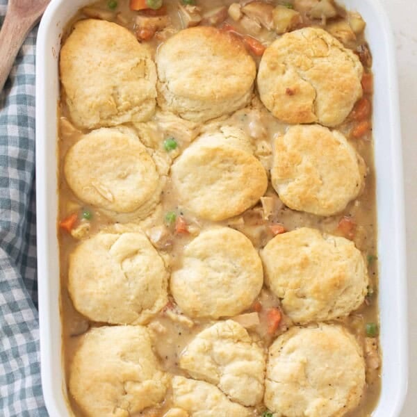 overhead photo of sourdough chicken pot pie in a white baking dish on a blue and white checked towel.