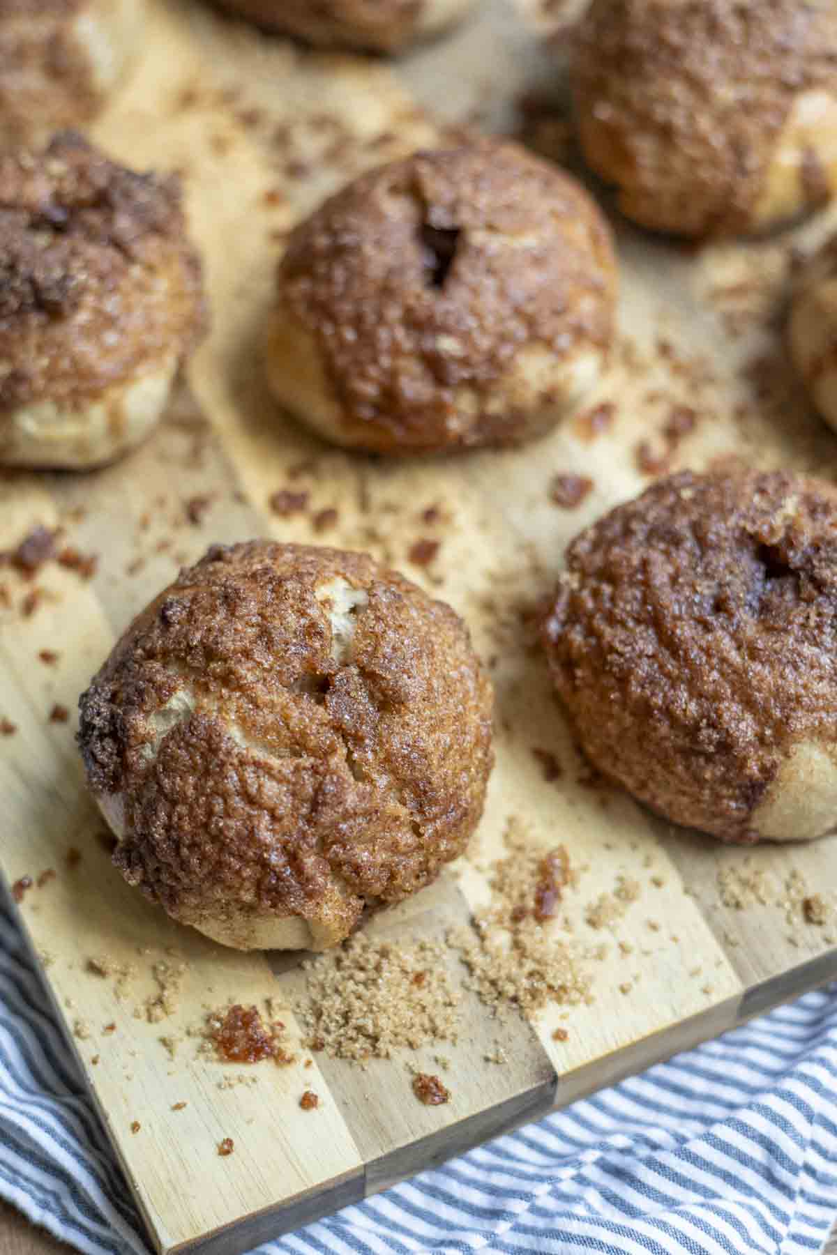 cinnamon crunch sourdough bagels on a wood cutting board with sugar sprinkled all over the cutting board