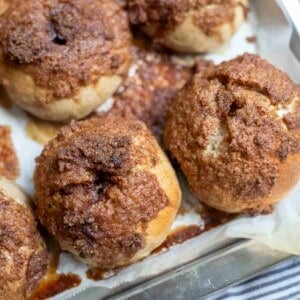 four sourdough cinnamon crunch bagels on a parchment lined backing sheet on a blue stripped towel