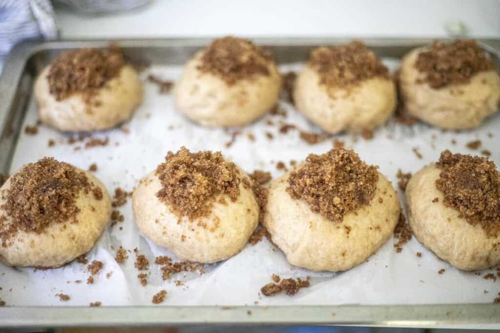 unbaked bagels with cinnamon sugar topped on each bagel on a parchment lined baking sheet.