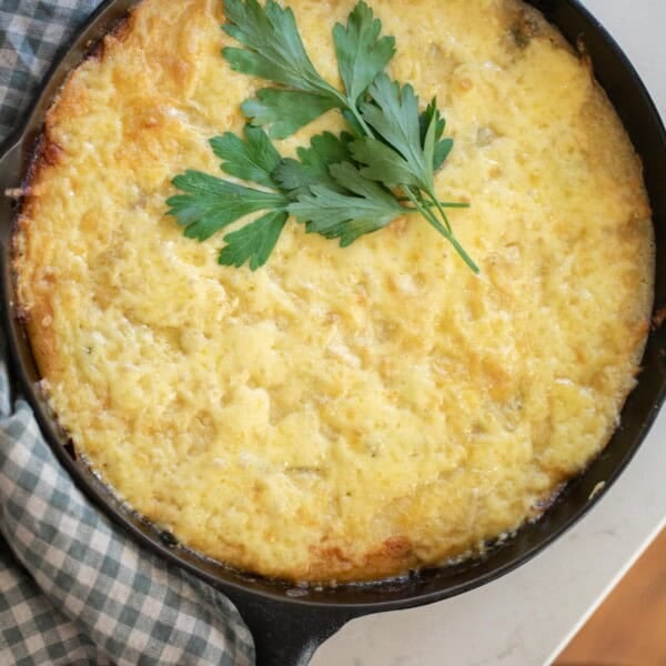 overhead photo of sourdough skillet topped with cheese and parsley in a cast iron skillet on white towel