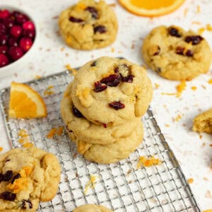 Cranberry cookies stacked three high on a cooling rack.