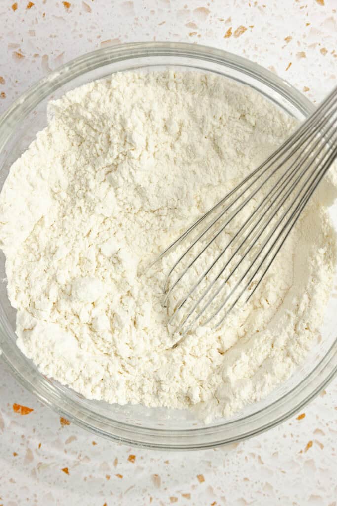 Dry ingredients for cranberry cookies in a bowl with a whisk sticking out of it.