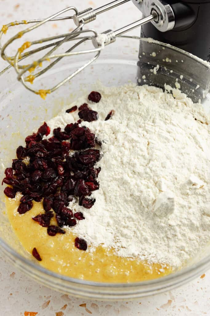 Dry ingredients and cranberries added to the wet ingredients in a bowl.