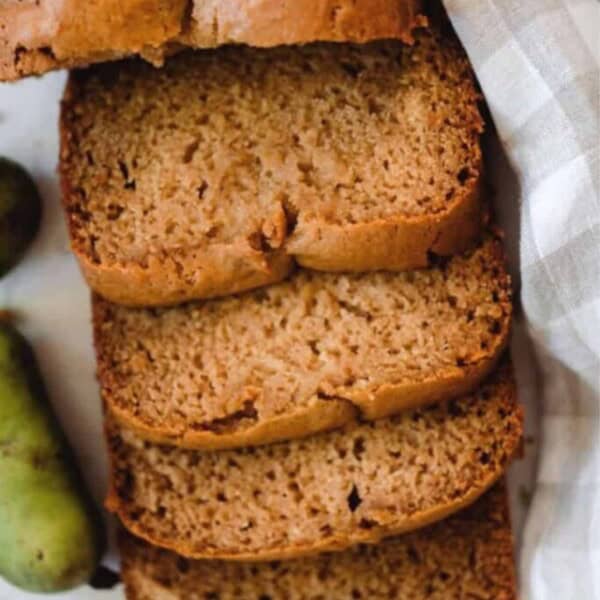 overhead photo of pawpaw bread sliced on a white and tan checked towel