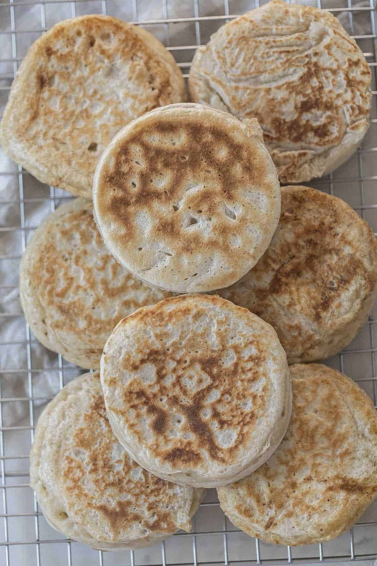 Sourdough crumpets stacked on a cooling rack.