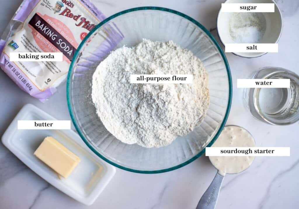 Ingredients for sourdough crumpets arranged on a marble countertop.