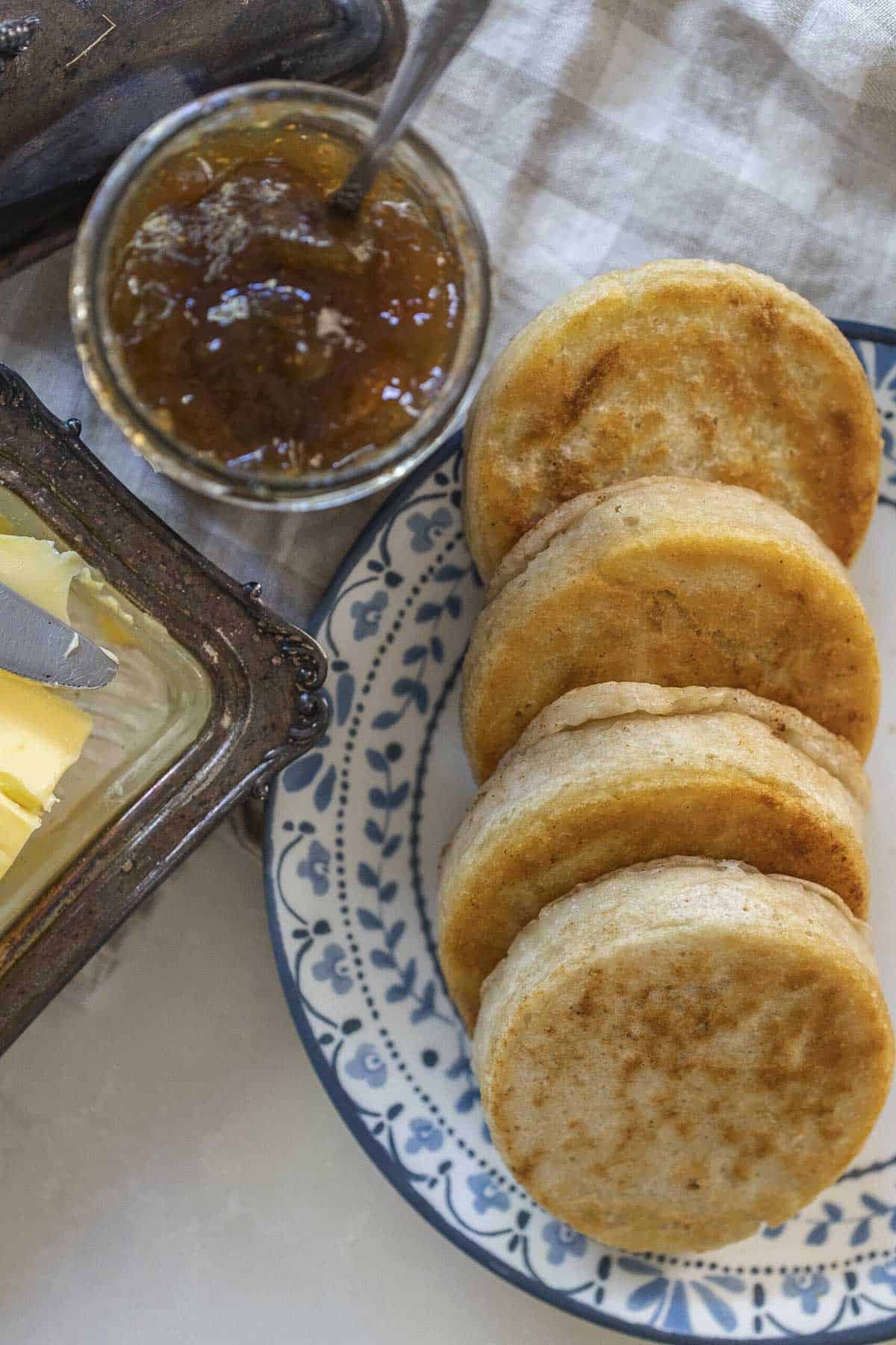 Sourdough crumpets on a plate with jam and butter.