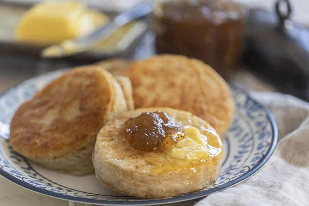 Sourdough crumpets on a plate topped with butter and jam.