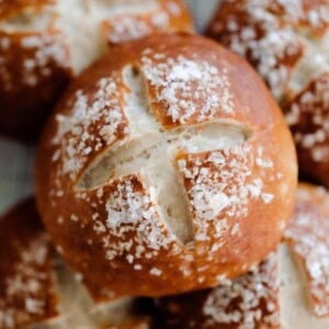 overhead photo of 5 sourdough pretzel rolls stacked in two layers on a towel