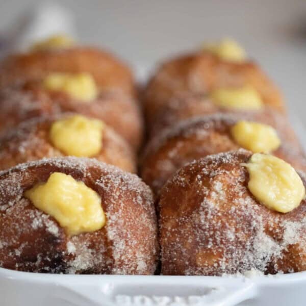 brioche donuts in a white casserole dish with a copper pot in background