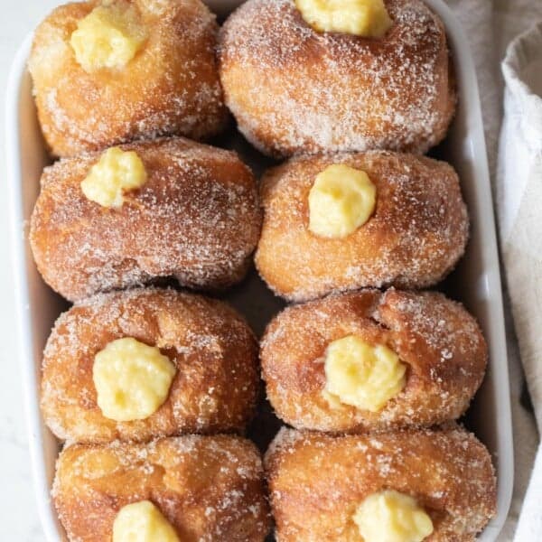 Brioche donuts filled with custard in a gray pan on a white counter top