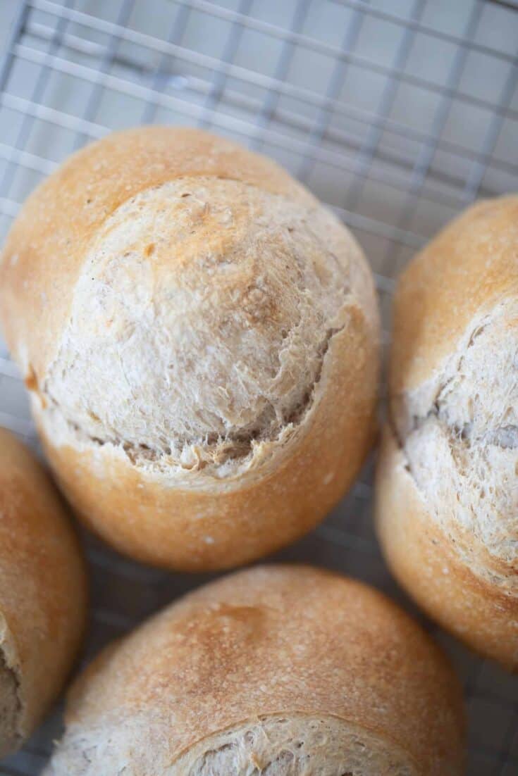 4 mini sourdough loaves next to each other on a wire rack on top of a white countertop