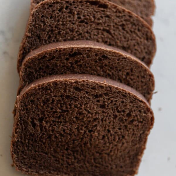 overhead photo of four slices of sourdough pumpernickel bread laying on a white countertop