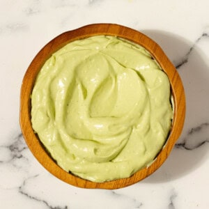 Avocado aioli in a terracotta bowl on a white countertop