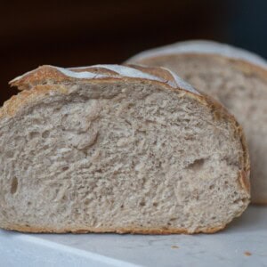 Two halves of a low hydration sourdough bread on a white countertop