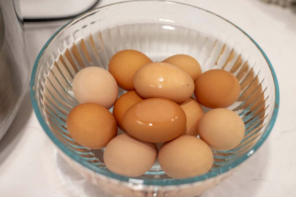 Hard boiled eggs under cold water in a bowl.