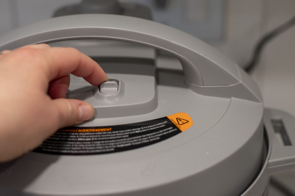 Hand releasing the pressure on an Instant Pot.