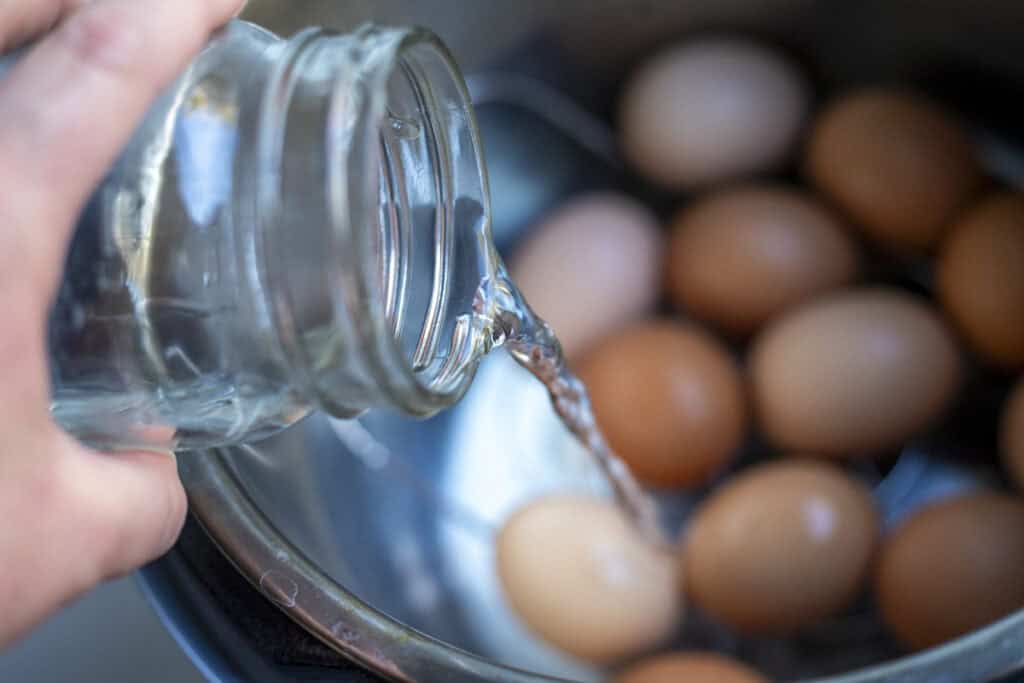 Adding water to the Instant Pot with eggs.