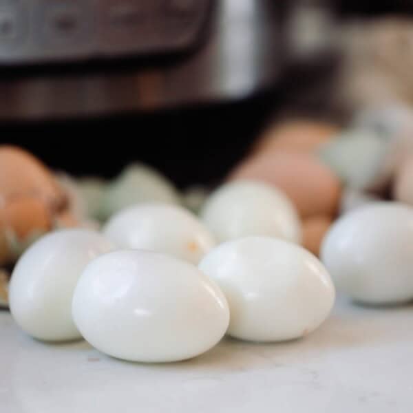 peeled hard boiled eggs on a white counter with more eggs and an Instant Pot in the background