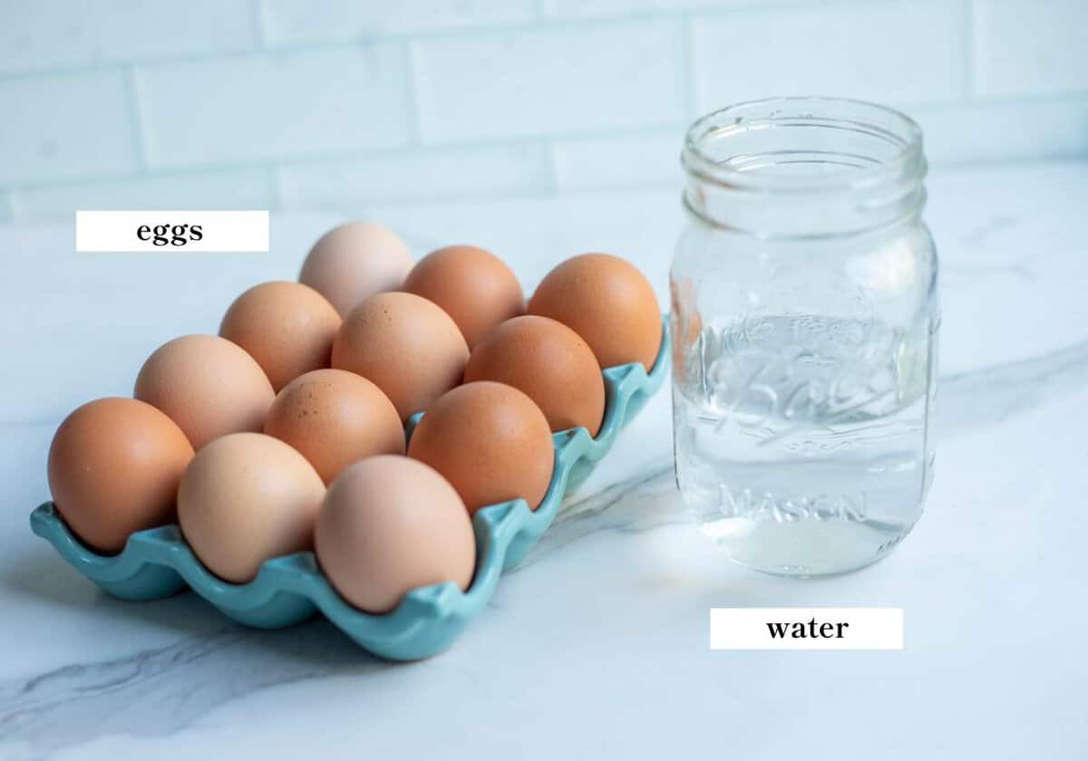 Eggs in an egg holder and a glass of water on a countertop.