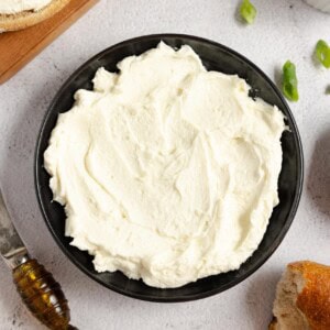 close up of homemade cream cheese in a black bowl on a white countertop