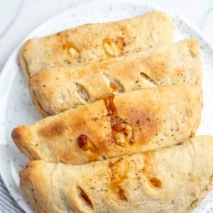 four calzones on a blue and white speckled plate on a marble countertop