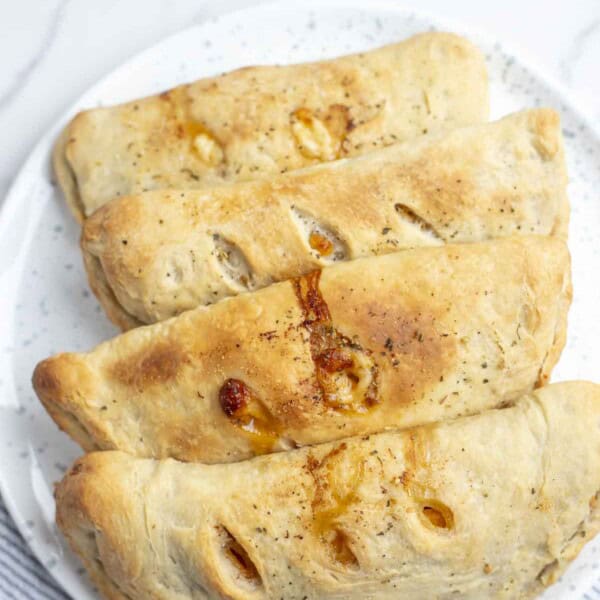 four calzones on a blue and white speckled plate on a marble countertop