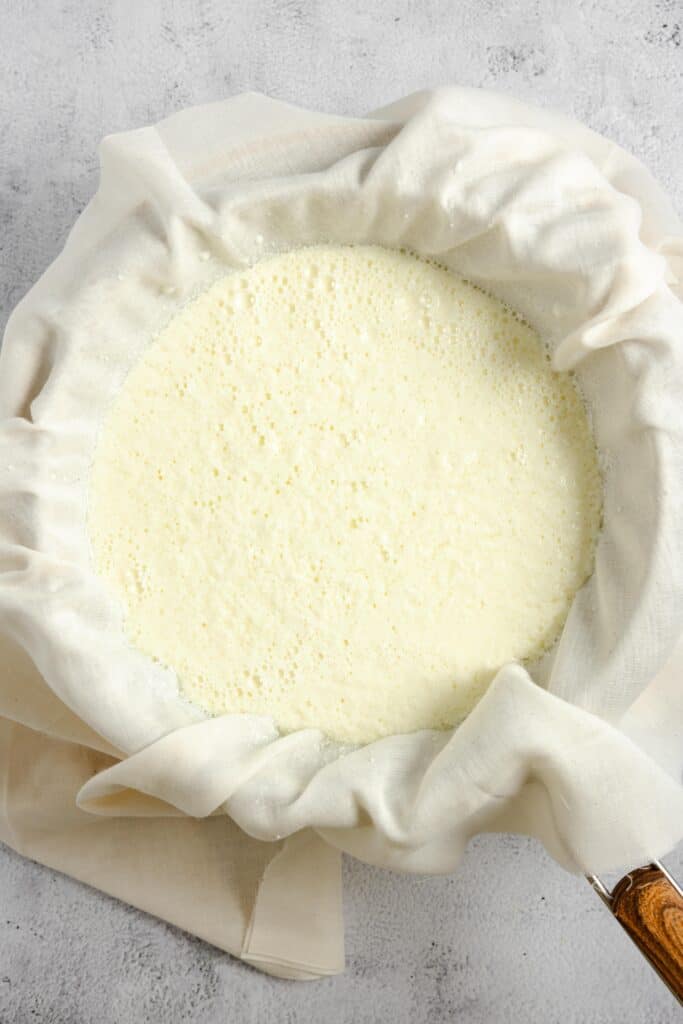straining ricotta cheese through cheese cloth and a strainer
